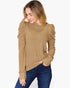 A woman wearing a ribbed knit mock neck sweater in camel brown with dramatic ruched puffed sleeves, paired with dark blue jeans, against a plain white background.