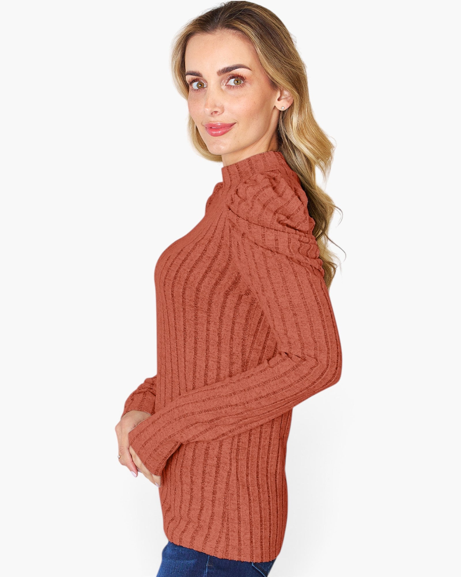 A woman wearing a rust-colored ribbed knit mock neck sweater, shown from a side profile against a plain white background.