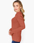 A woman wearing a rust-colored ribbed knit mock neck sweater, shown from a side profile against a plain white background.