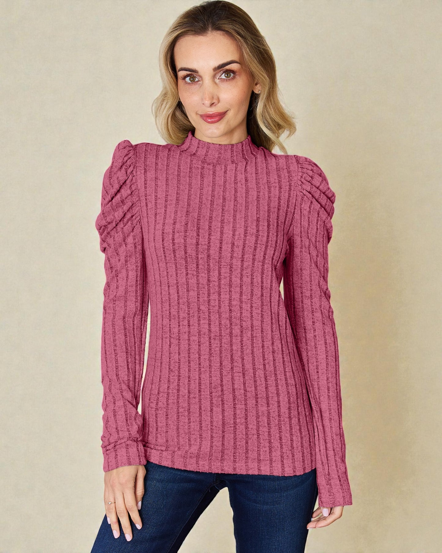 Woman wearing a pink textured sweater against a beige background