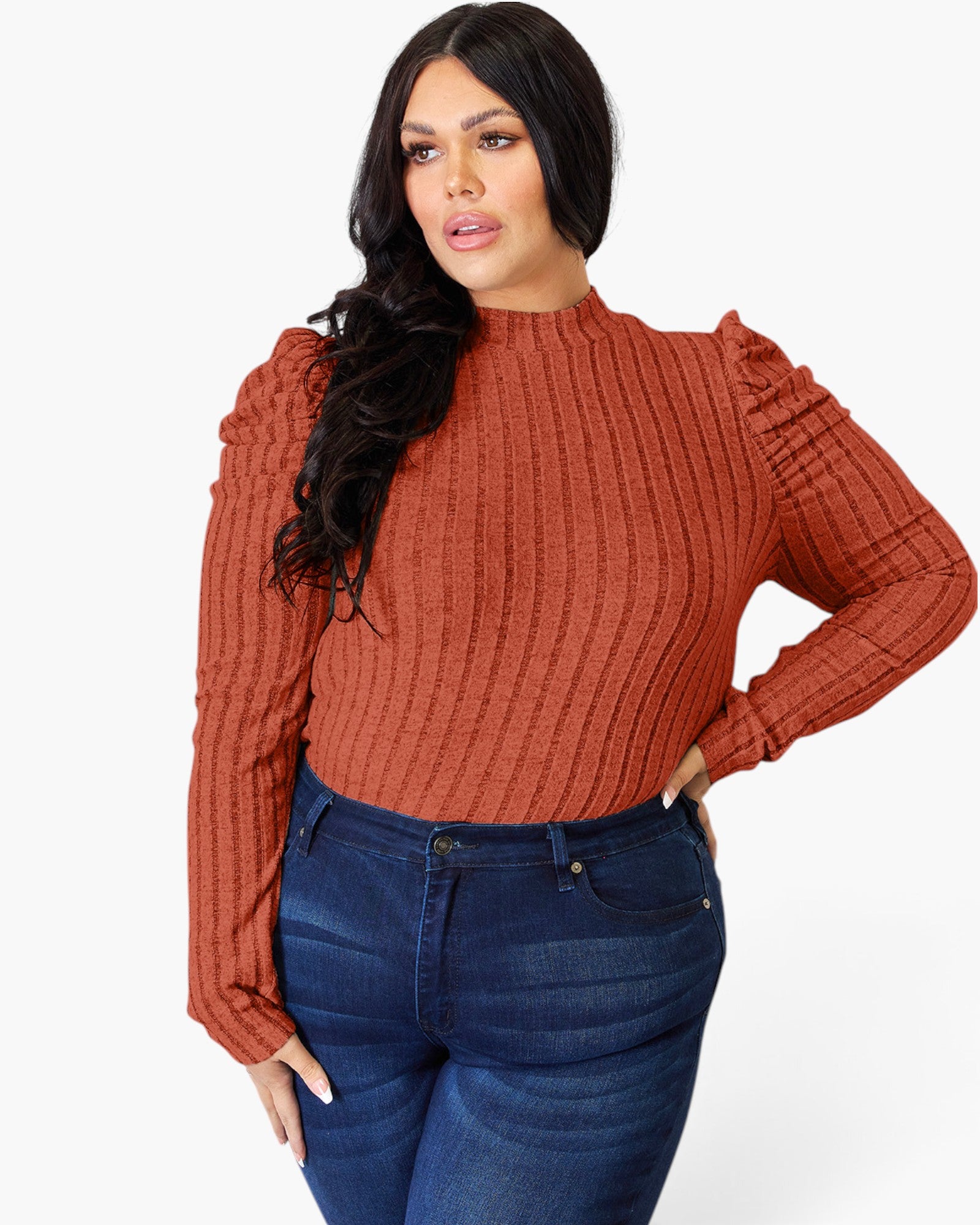 A woman modeling a ribbed long-sleeve mock neck top in a rust orange color, paired with dark blue jeans, against a plain white background.