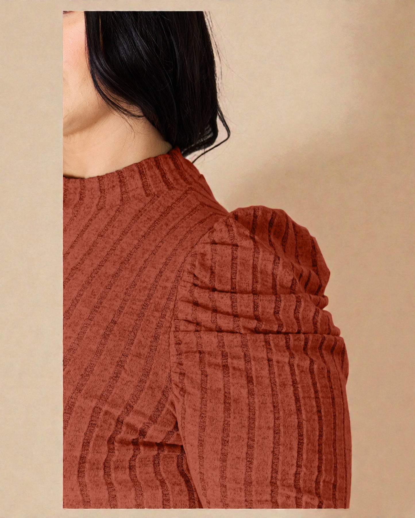 Close-up of a person wearing a rust-colored ribbed sweater against a beige background