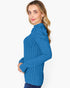 A woman wearing a bright blue ribbed knit mock neck sweater, shown from a side profile against a plain white background.
