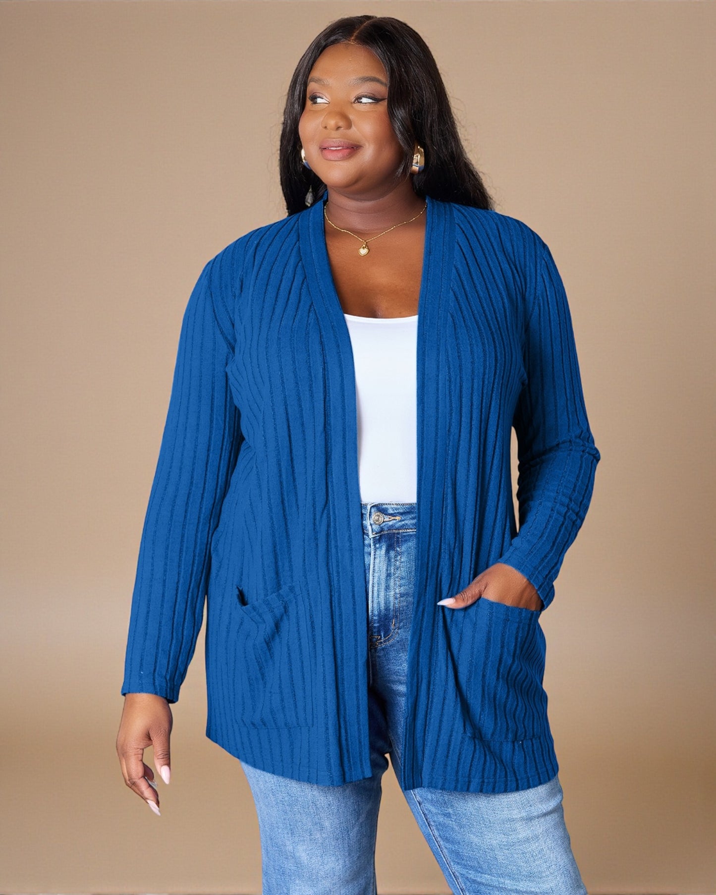 Woman wearing a blue cardigan over a white top and jeans on a beige background