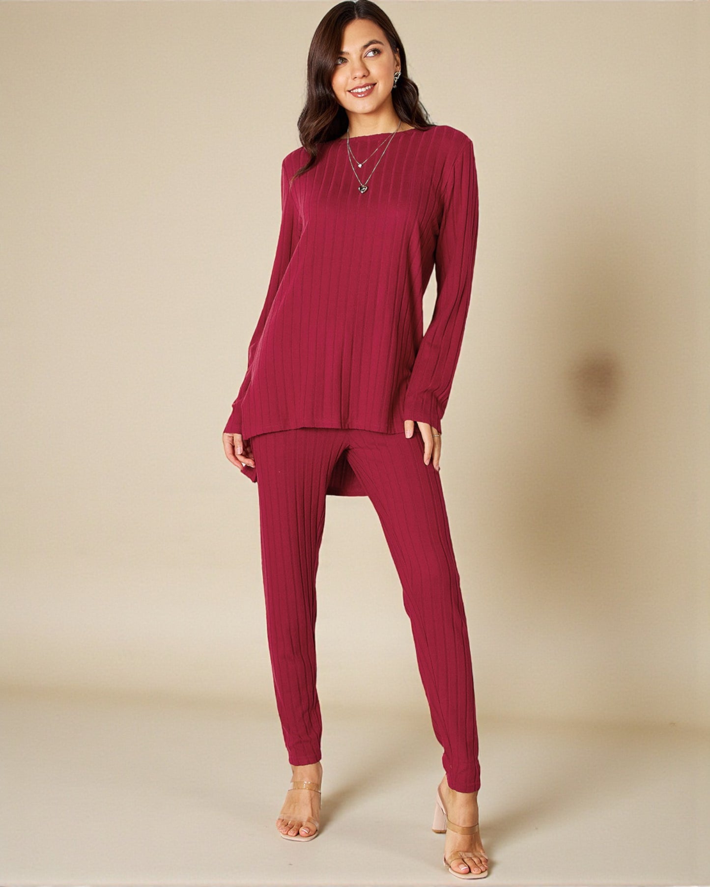 Woman wearing a burgundy long-sleeve top and pants on a beige background