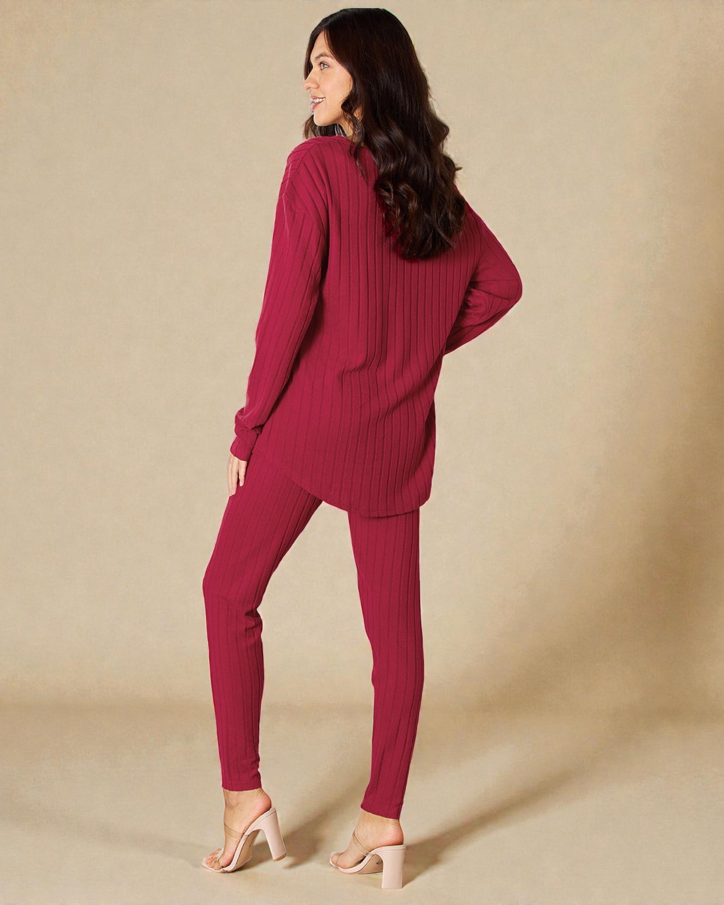 Woman wearing a maroon ribbed sweater and pants on a beige background