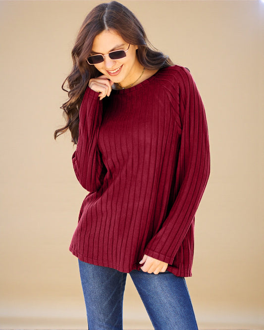 Woman wearing a burgundy sweater and blue jeans against a beige background