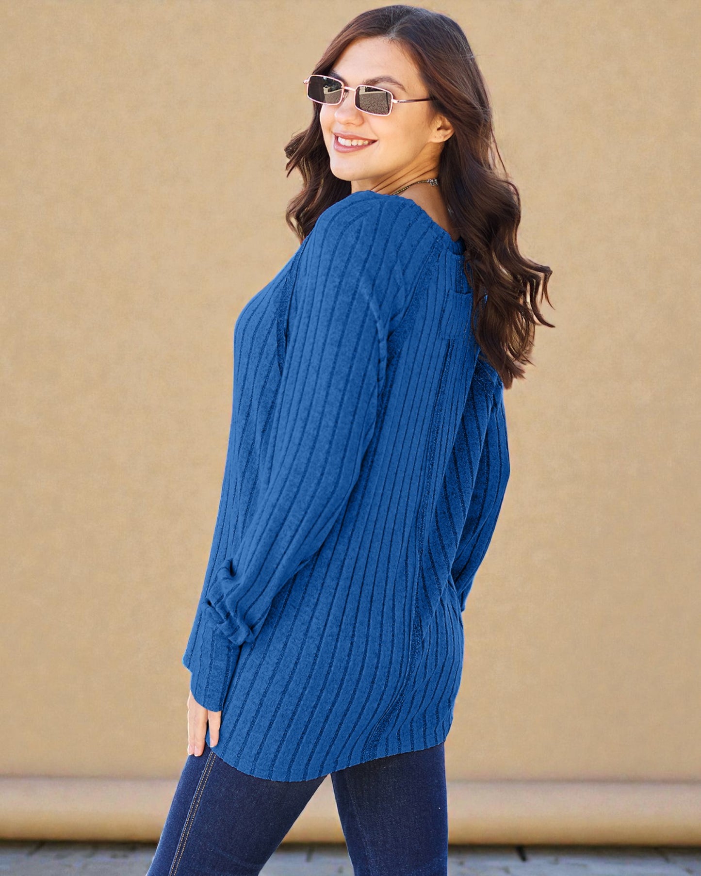 Woman wearing a blue sweater against a beige wall