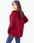 A woman wearing a ribbed knit long-sleeve top in deep burgundy, paired with blue jeans and sunglasses, photographed against a plain white background.