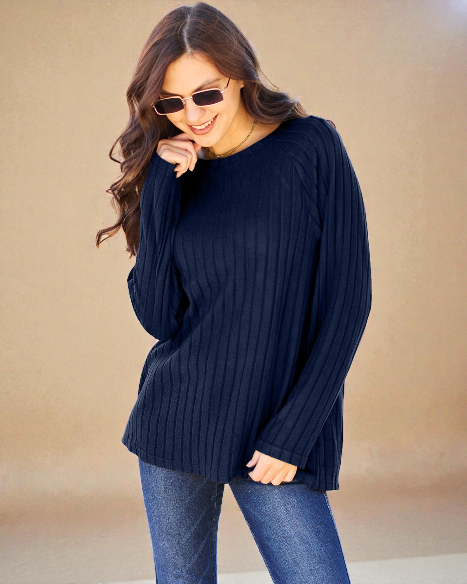 Woman wearing a navy sweater and blue jeans against a beige background