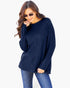 A woman wearing a navy blue ribbed knit long-sleeve sweater and blue jeans, posing against a light gray background.