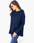 A woman wearing a navy blue ribbed knit long-sleeve top and blue jeans, photographed against a plain light background.