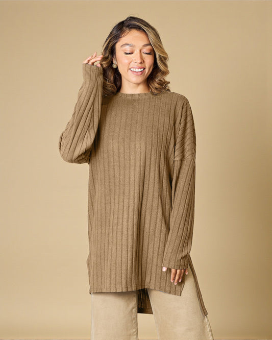 Woman wearing a ribbed brown sweater against a beige background