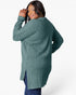 A woman wearing a ribbed knit long-sleeve tunic sweater in a muted teal green, shown from the back against a light gray studio background.