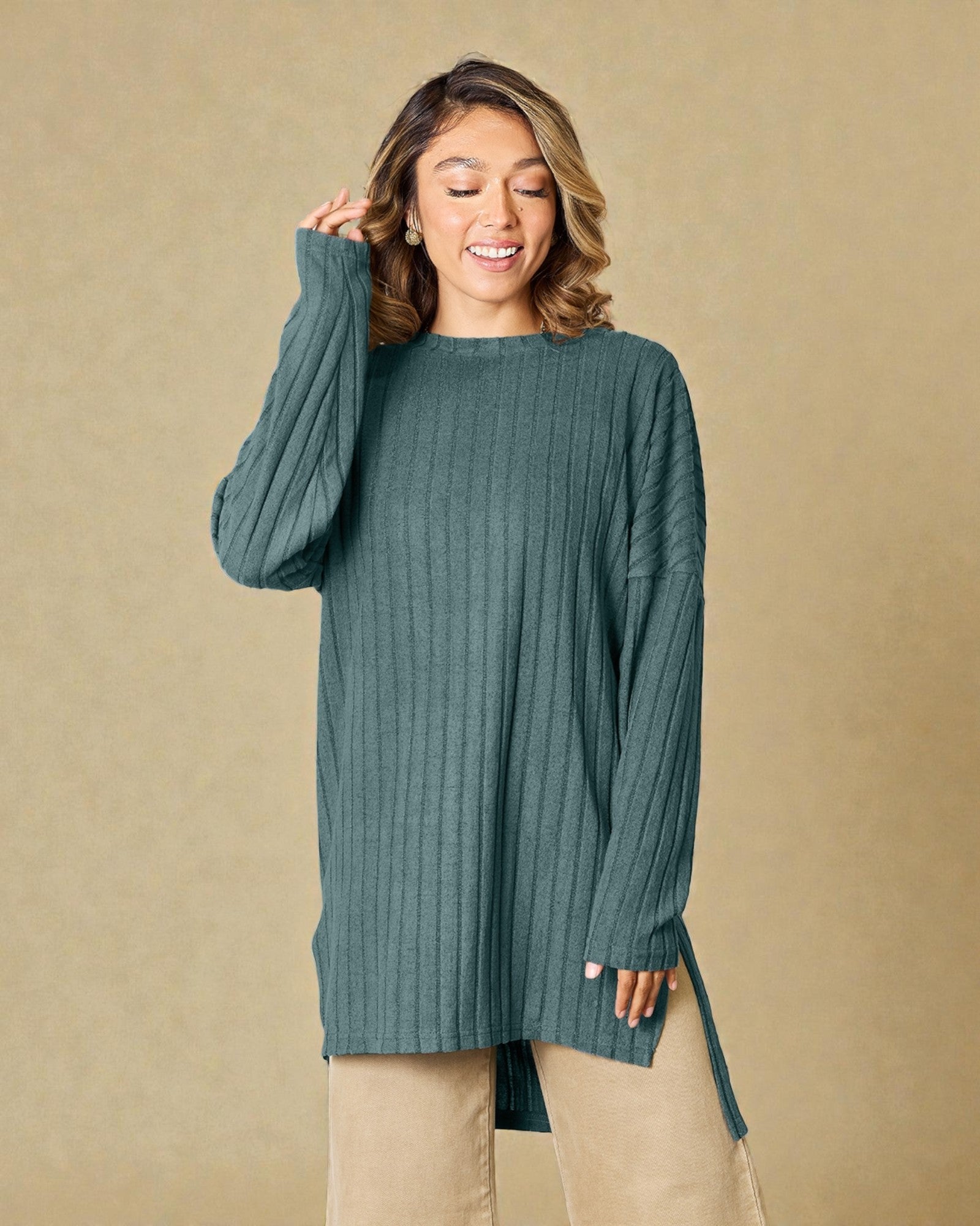 Woman wearing a teal sweater against a beige background