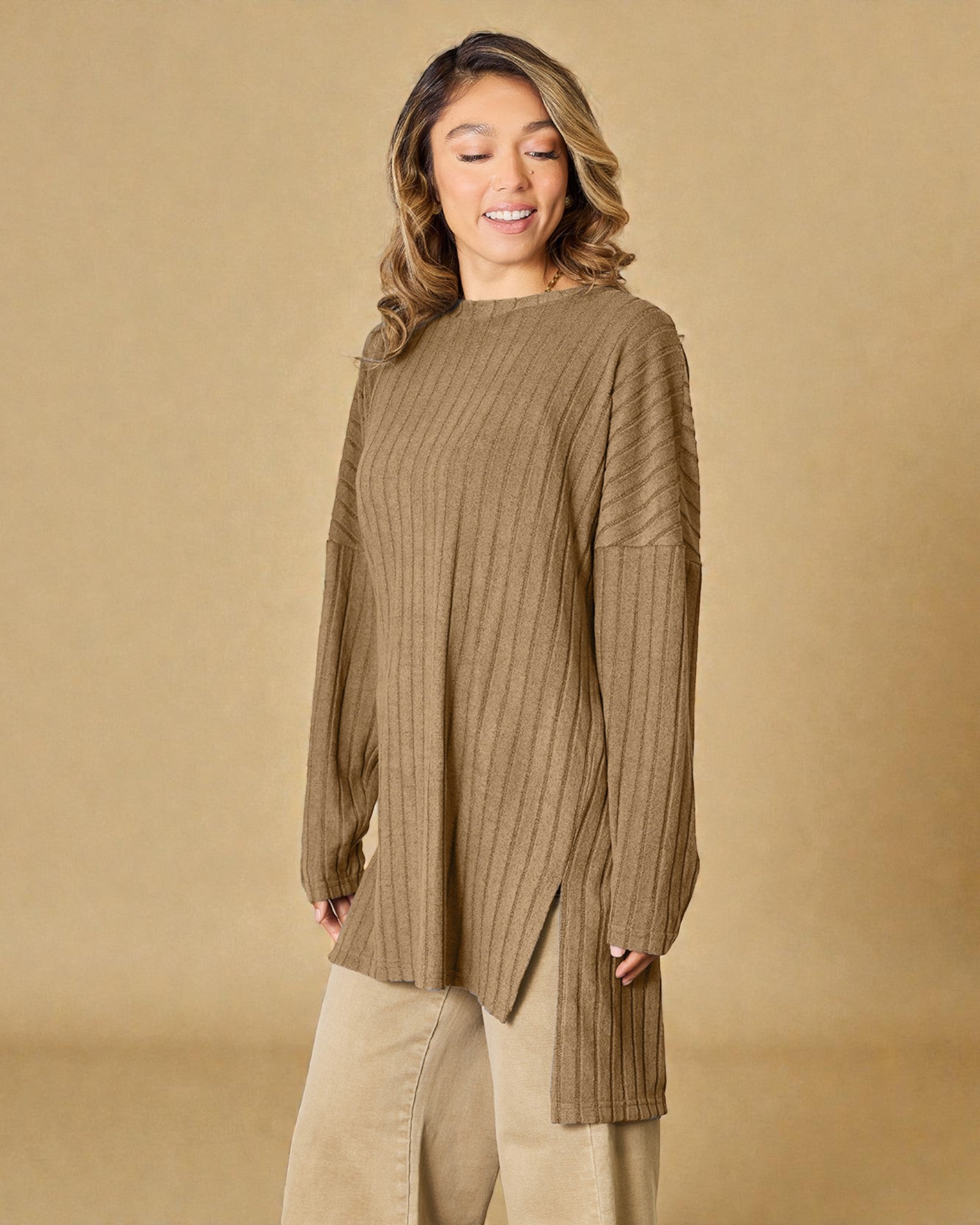 Woman wearing a ribbed brown sweater against a beige background
