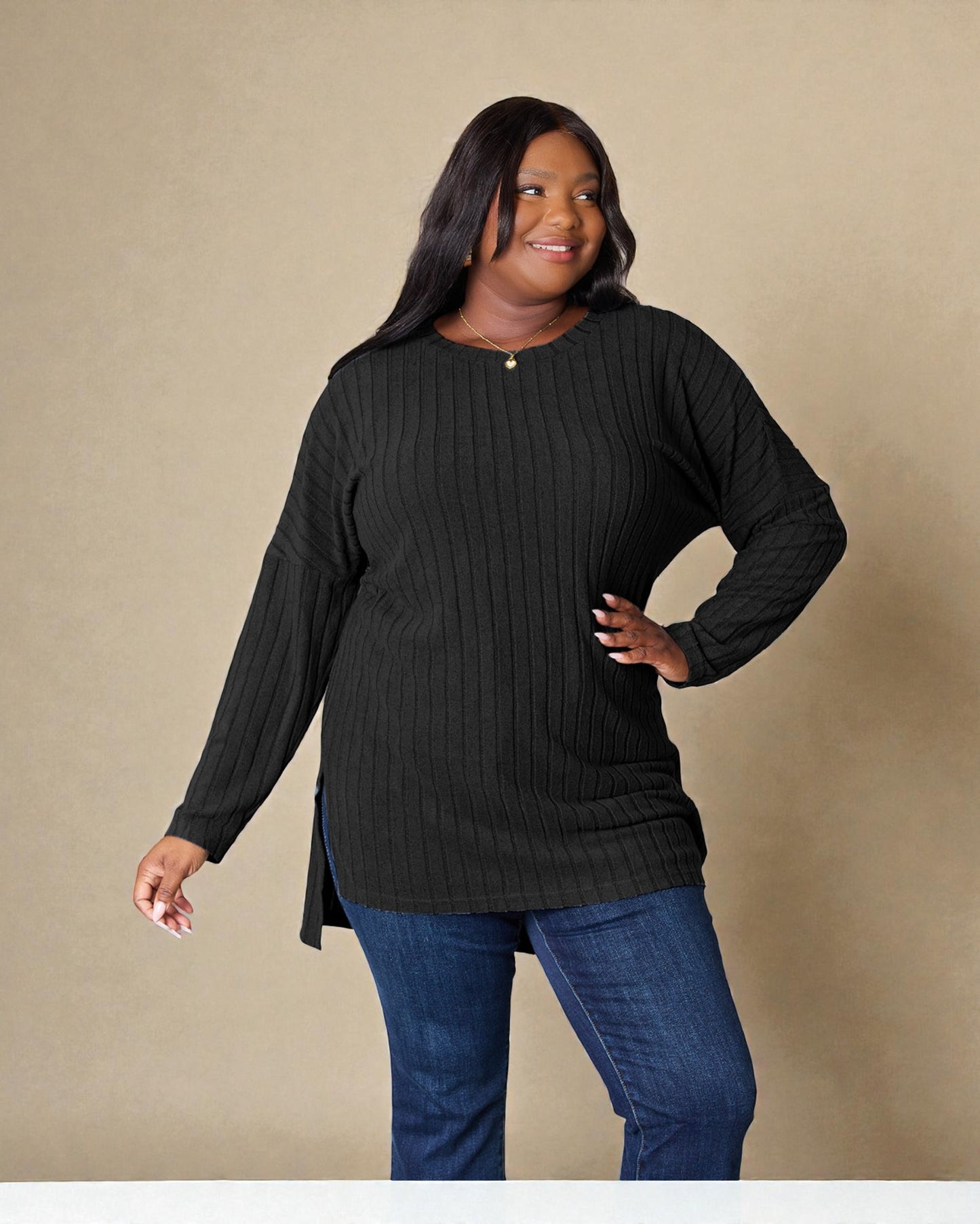 Woman wearing a black sweater and blue jeans against a beige background