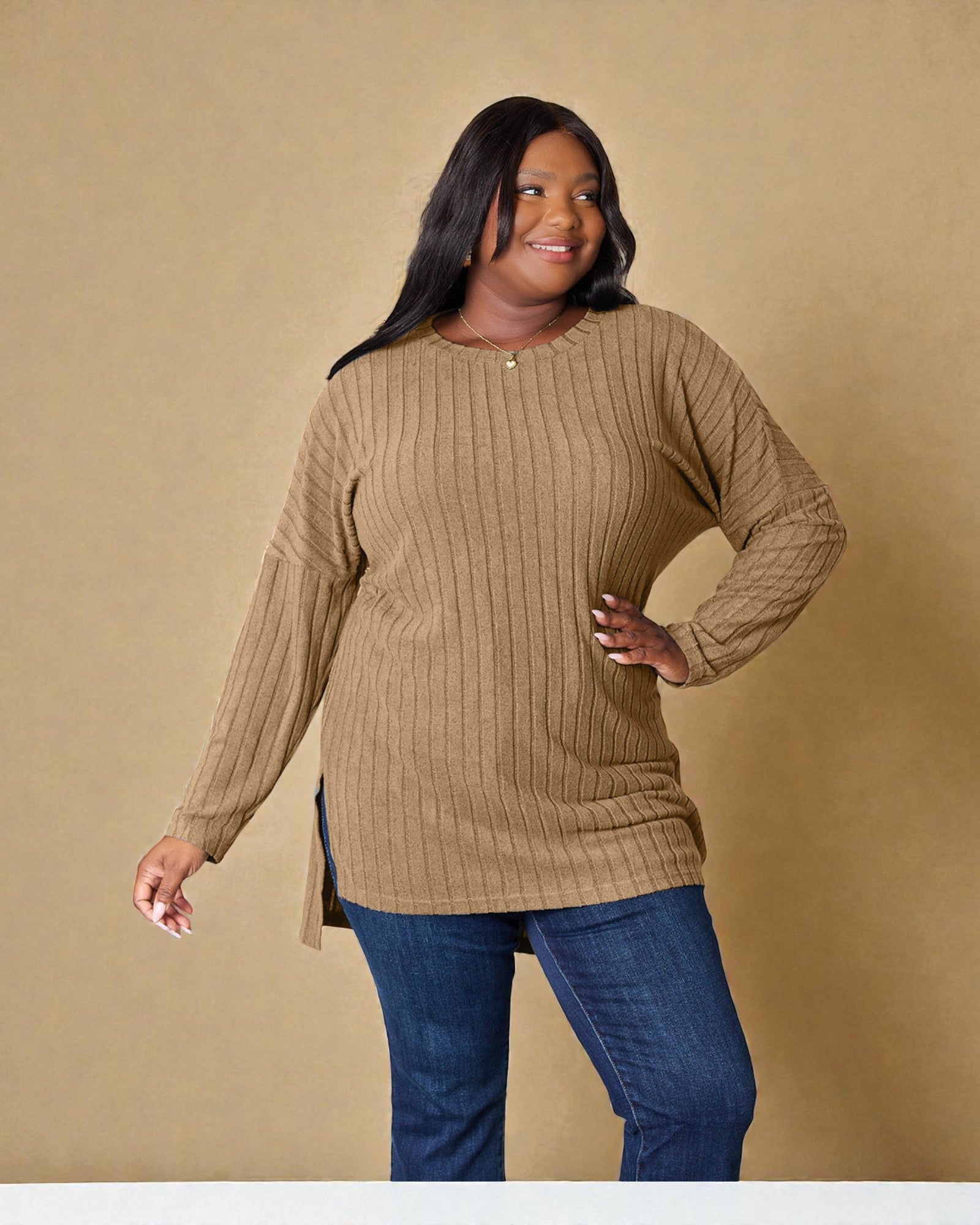 Woman wearing a beige sweater and blue jeans against a beige background