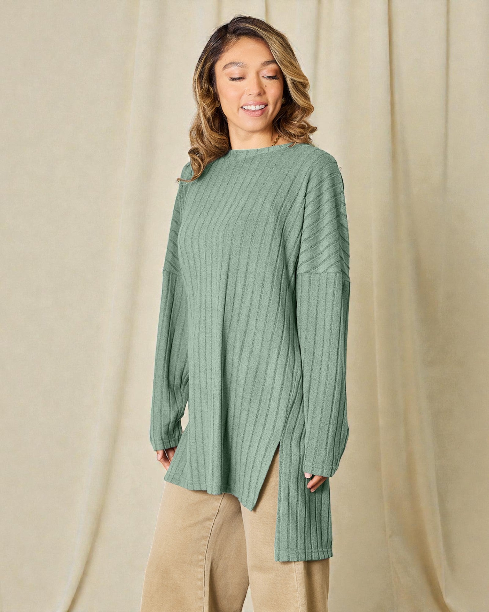 Woman wearing a green ribbed sweater against a beige background