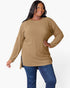 A woman modeling a ribbed knit long-sleeve tunic top in camel brown, paired with blue jeans, against a plain white studio background.