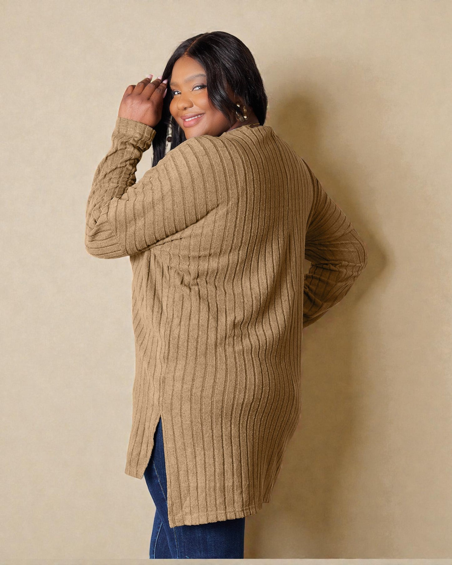 Woman wearing a beige ribbed cardigan against a beige wall