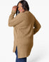 A woman wearing a camel-colored ribbed knit tunic sweater with blue jeans, photographed from the back against a clean white studio background.