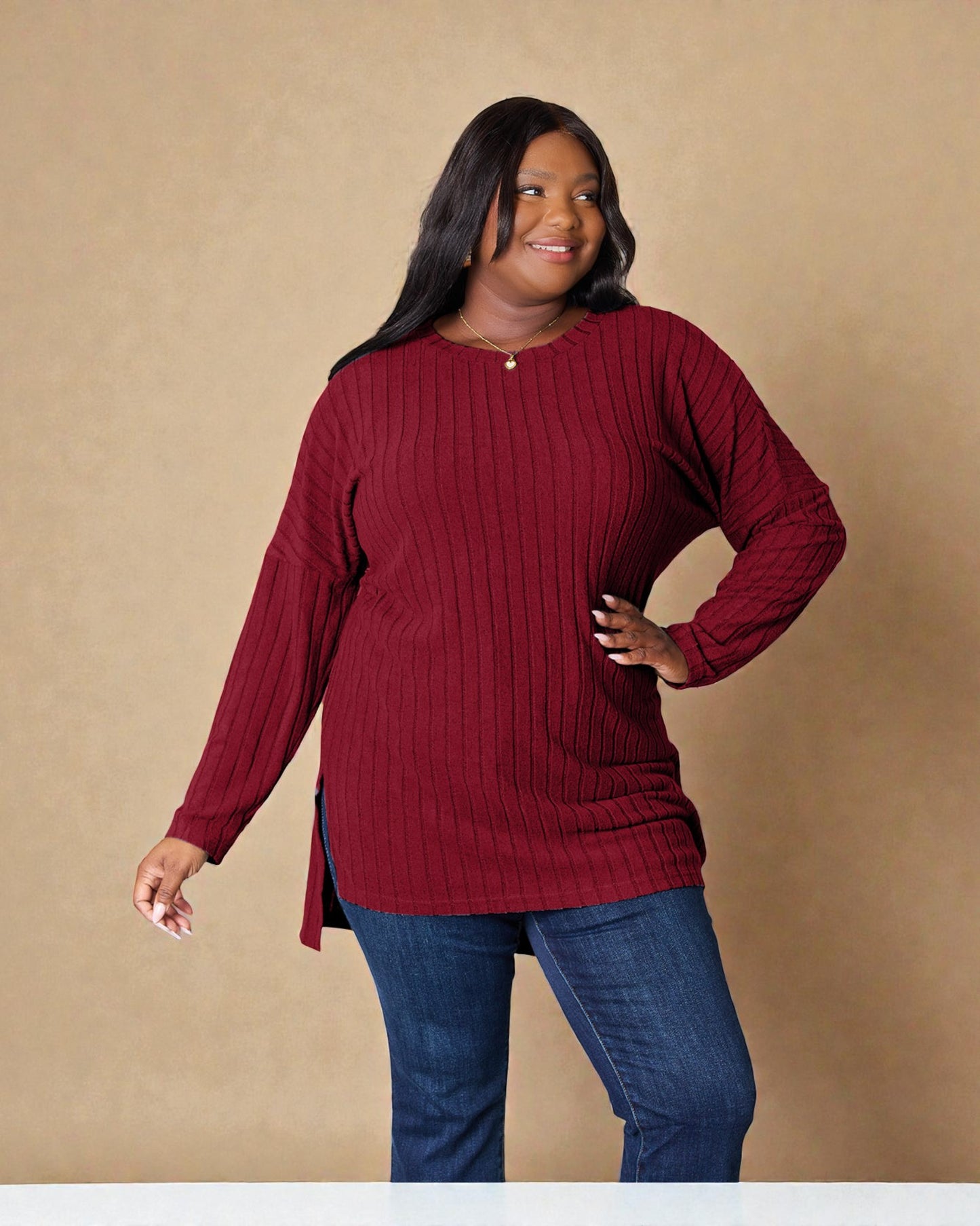 Woman wearing a red sweater and blue jeans against a beige background