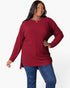 A woman modeling a long-sleeve ribbed knit tunic top in deep burgundy, paired with blue jeans, against a plain white studio background.