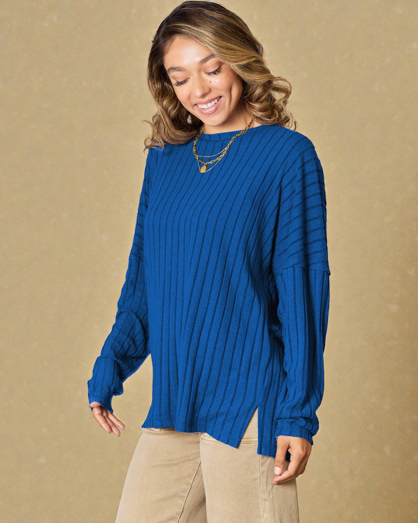 Woman wearing a blue ribbed sweater against a beige background