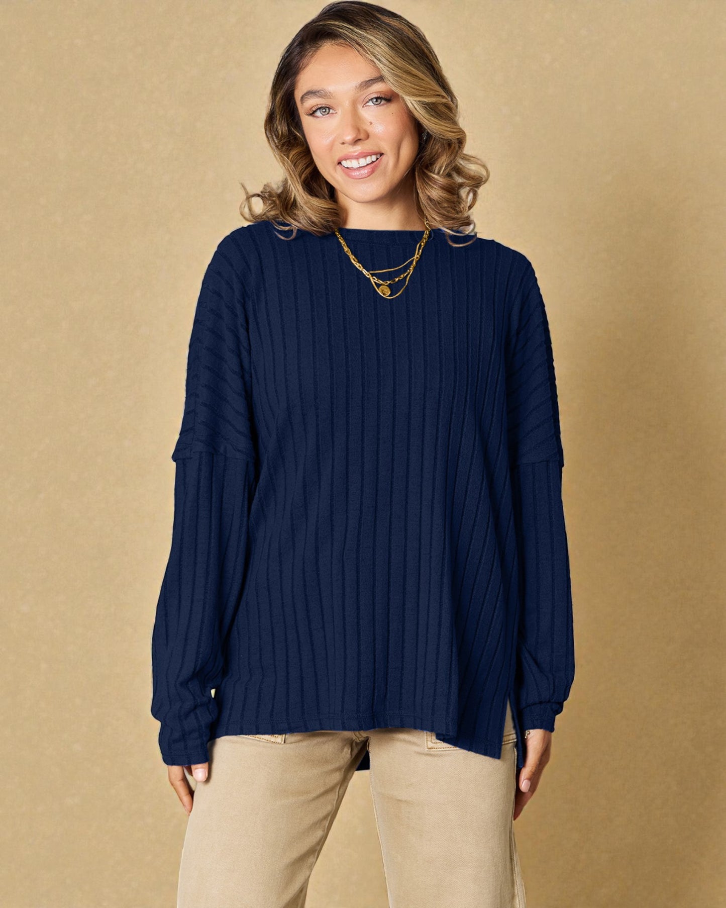 Woman wearing a navy sweater and beige pants against a beige background