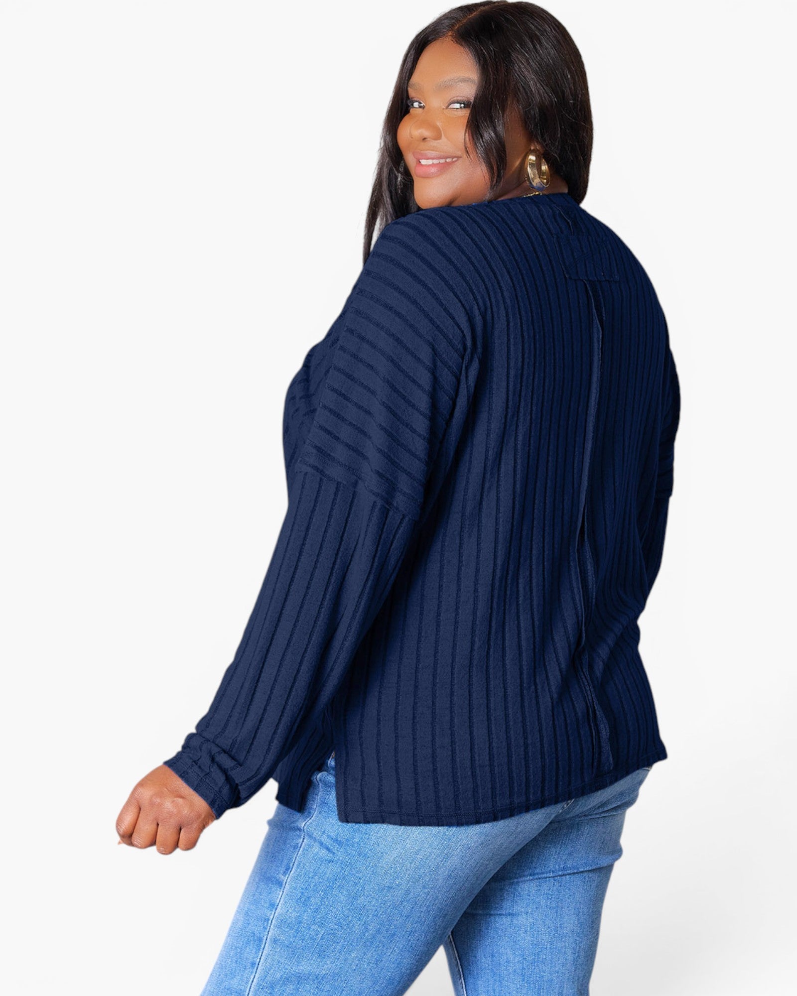 A woman wearing a navy blue ribbed knit long-sleeve sweater, shown from a three-quarter back angle against a plain white studio background.