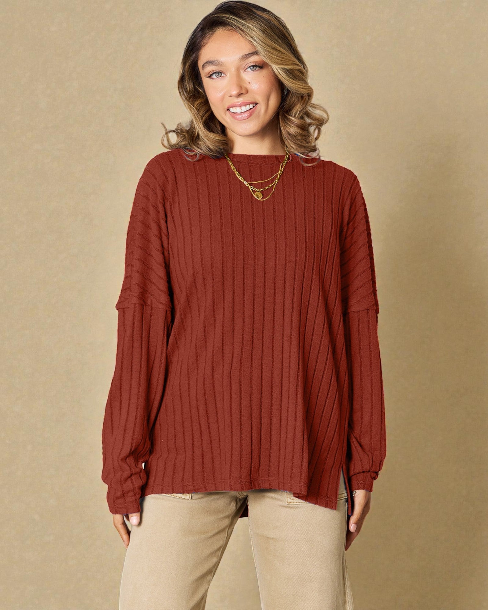 Woman wearing a red ribbed sweater against a beige background
