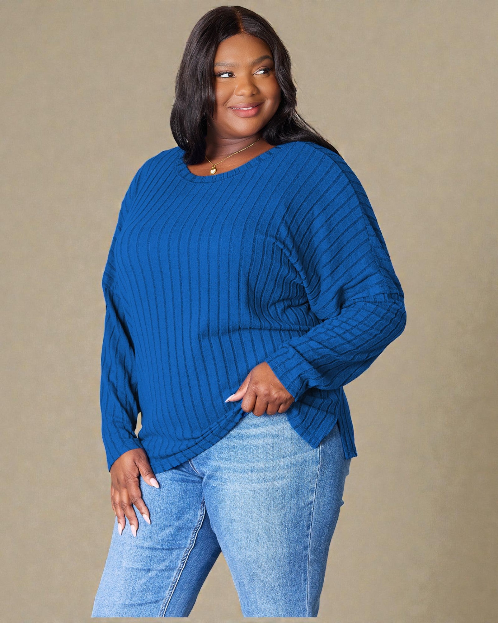 Woman wearing a blue sweater and jeans against a beige background