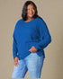 Woman wearing a blue sweater and jeans against a beige background
