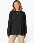 A woman wearing a black ribbed knit long-sleeve top with gathered elbow-length sleeves, paired with beige pants, against a plain white studio background.