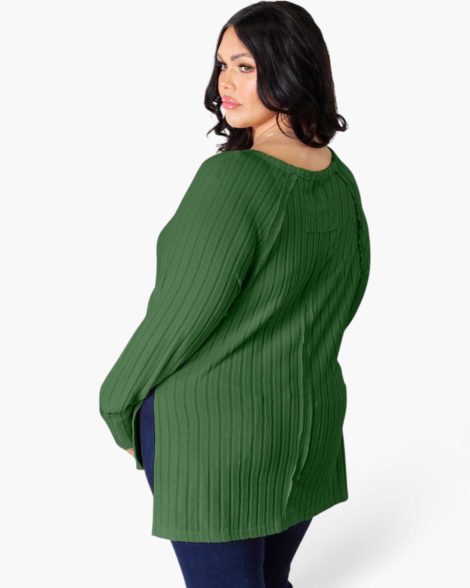 A woman wearing a green ribbed knit long-sleeve tunic top, shown from a three-quarters back view against a plain white studio background.