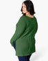 A woman wearing a green ribbed knit long-sleeve tunic top, shown from a three-quarters back view against a plain white studio background.