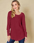 Woman wearing a red long-sleeve top against a beige background