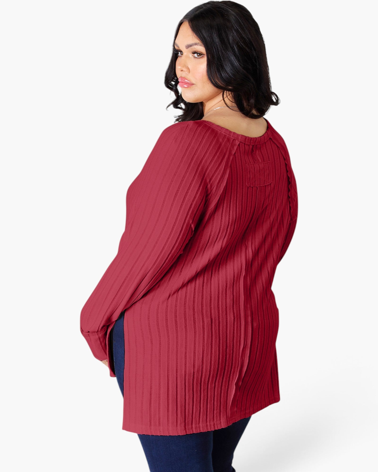 A woman wearing a ribbed long-sleeve tunic top in a deep red color, shown from a three-quarter back angle against a plain white background.