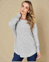 Woman wearing a gray sweater against a beige background