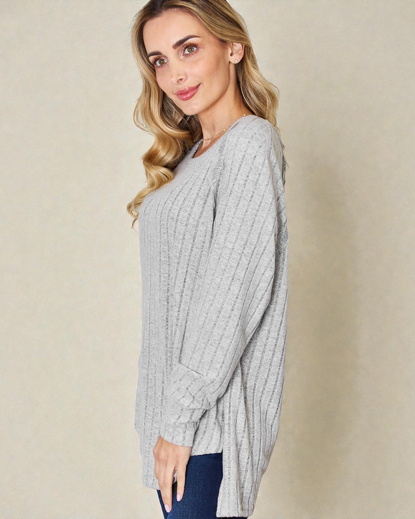 Woman wearing a gray ribbed sweater against a beige background