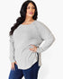 A woman modeling a light gray ribbed knit long-sleeve top with a boat neckline and side slit, paired with dark blue jeans against a plain white background.
