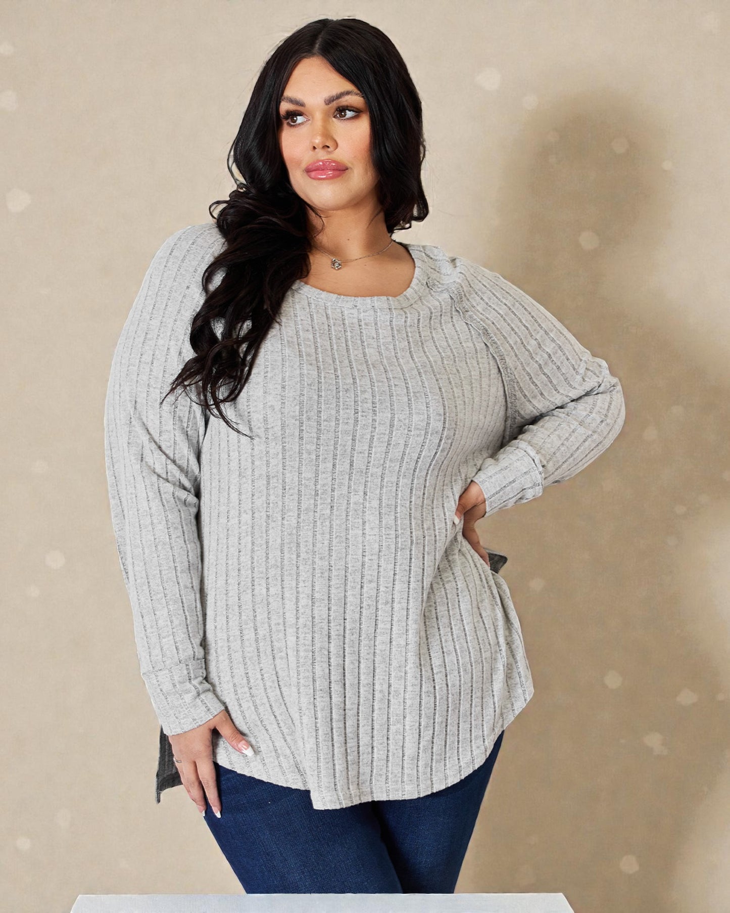 Woman wearing a gray ribbed sweater against a beige background