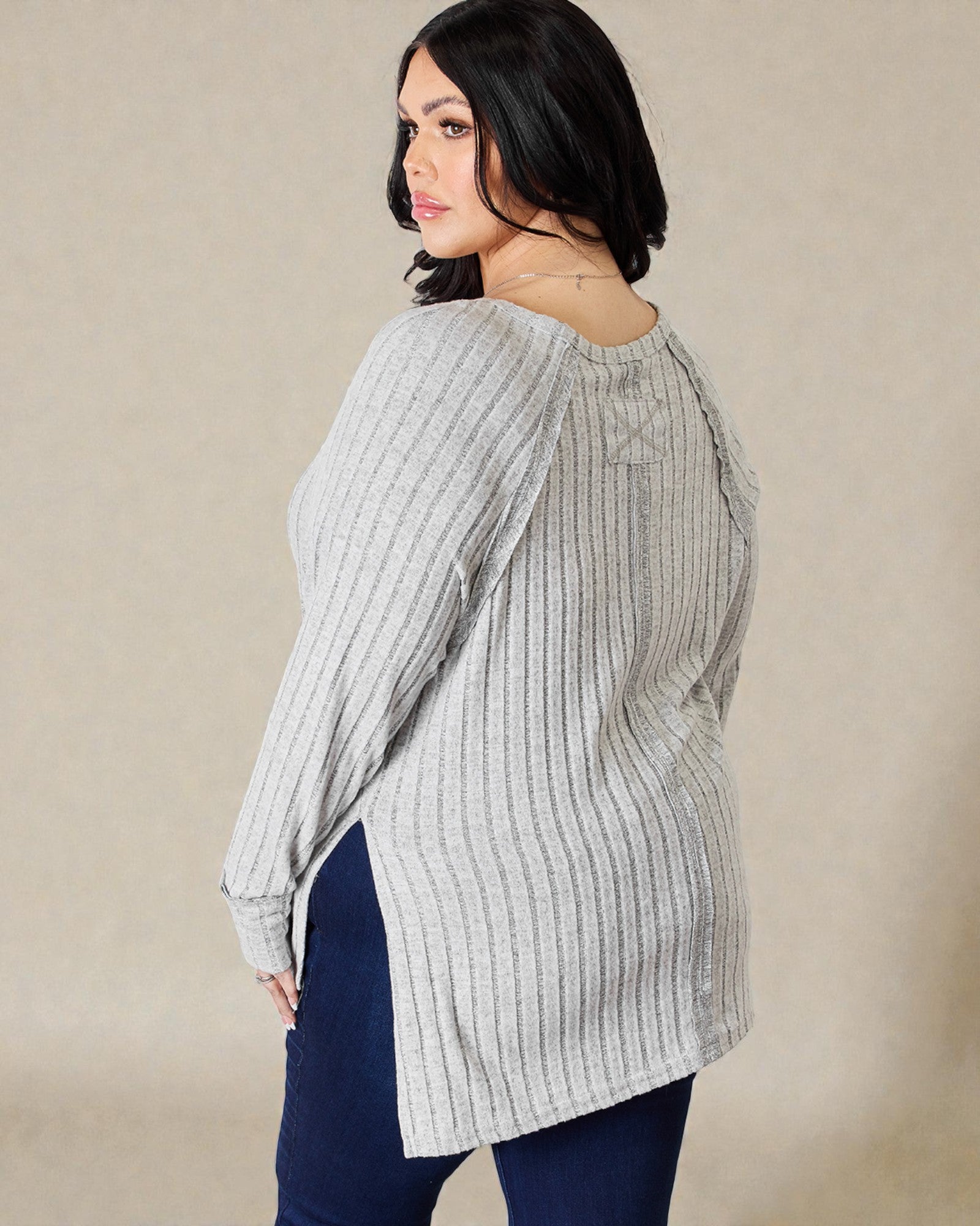 Woman wearing a light gray striped blouse against a beige background