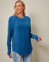 Woman wearing a blue ribbed sweater against a beige background