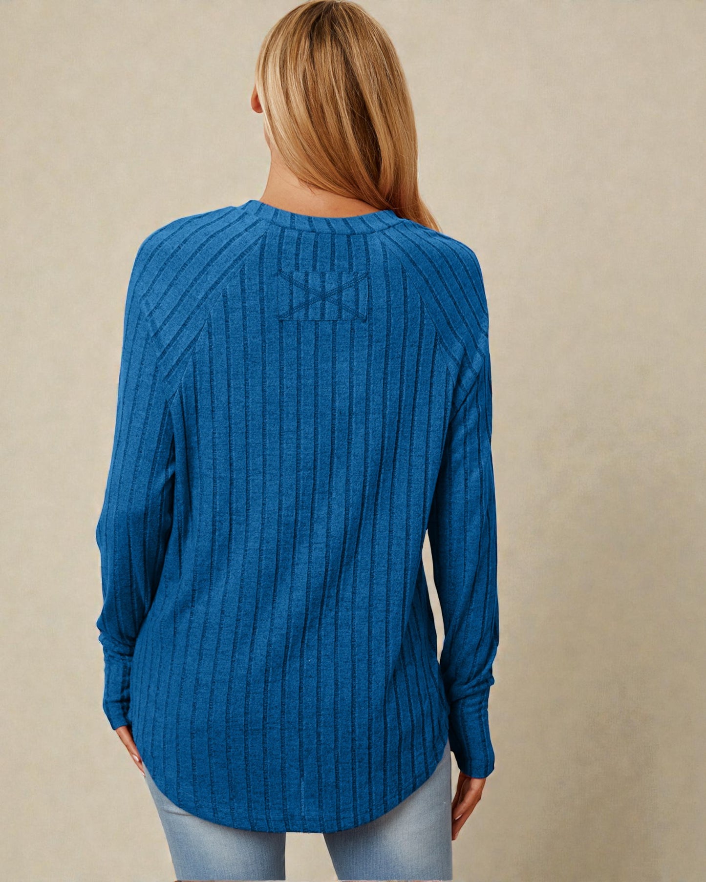 Person wearing a blue ribbed sweater on a beige background