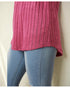 Person wearing a pink textured top and blue jeans on a beige background