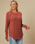 Woman wearing a rust-colored ribbed sweater against a beige background