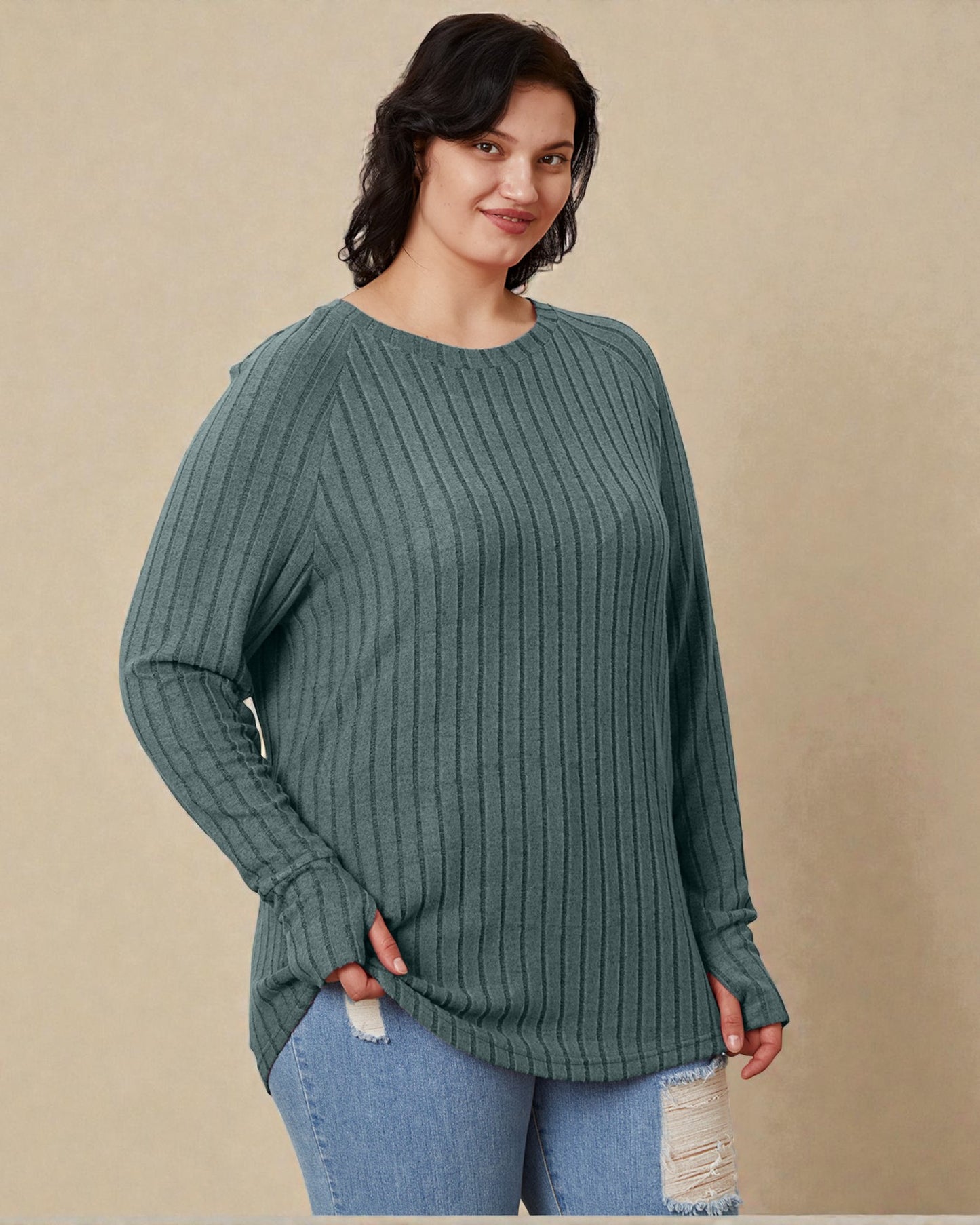 Woman wearing a green sweater and blue jeans against a beige background