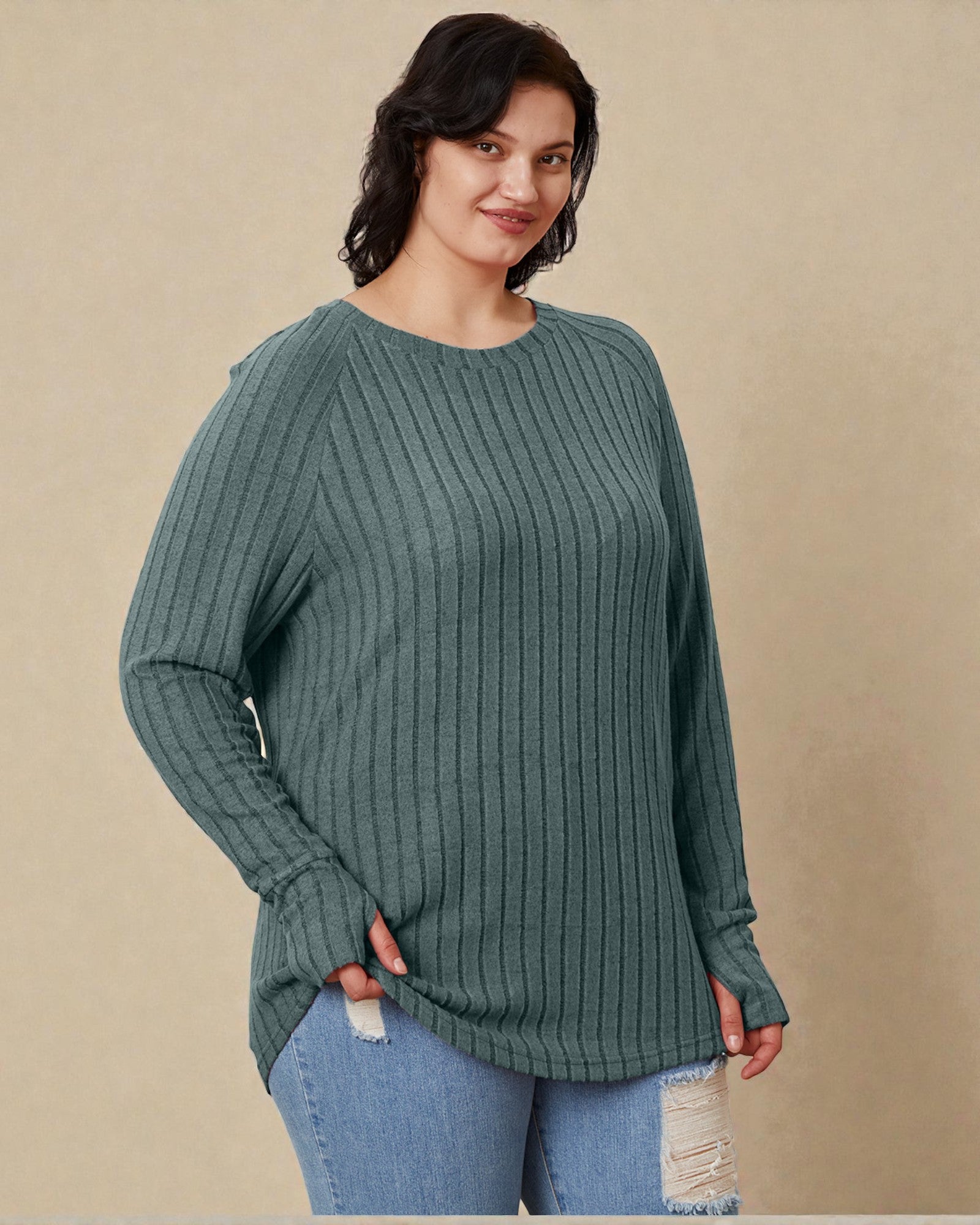 Woman wearing a green sweater and blue jeans against a beige background